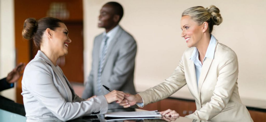 a receptionist handing over the pen to their guest at the reception counter