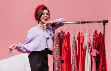 a women standing next to clothes hanging with a bag in her hand