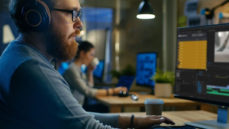 A person sitting in a video editing studio and editing a video on adobe premiere pro
