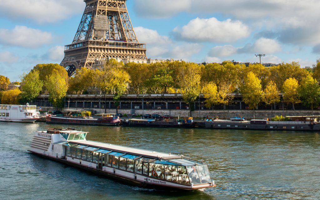 image of a boat carrying passengers on scene river in Paris passing the Eiffel Tower